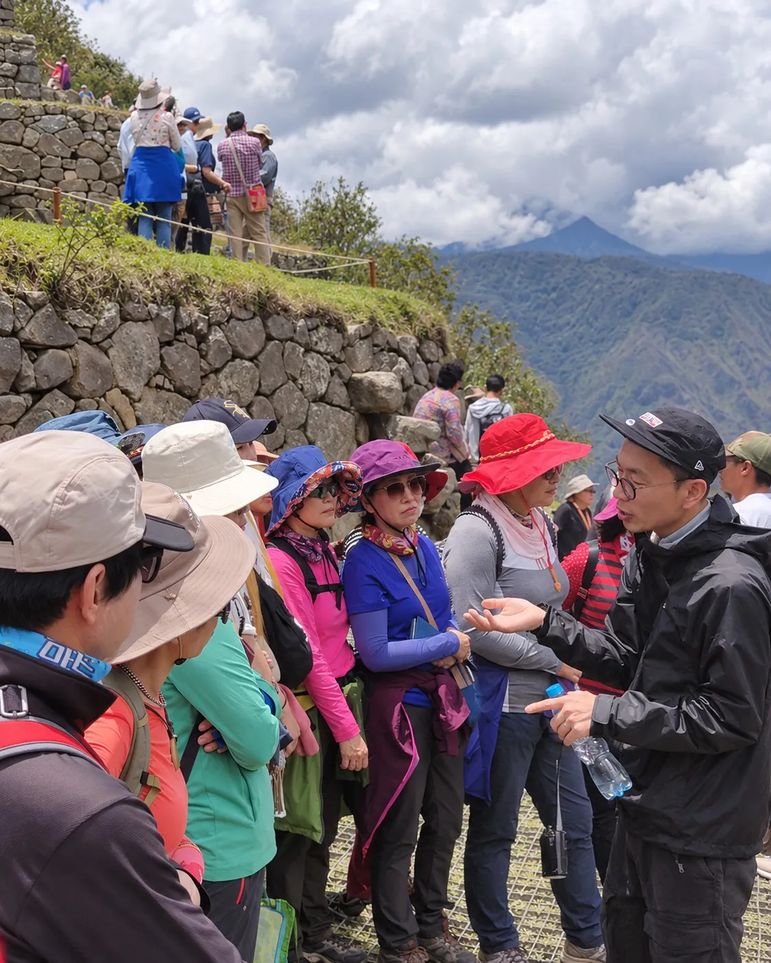 검은 모자와 안경을 쓰고 마추픽추에서 고객에게 설명하는 이문섭